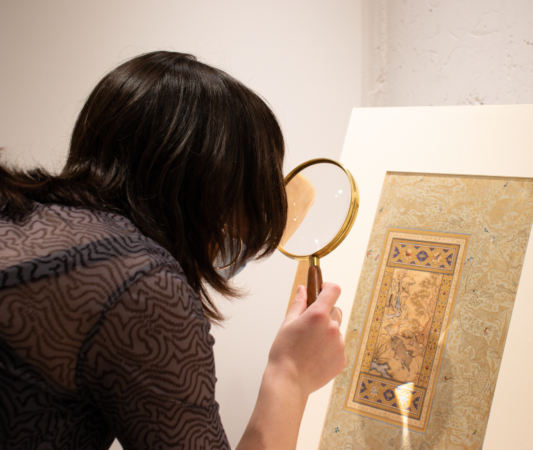 Honors Student at Nelson Atkins Image of an Honors College student looking through magnifying glass at a piece of art.