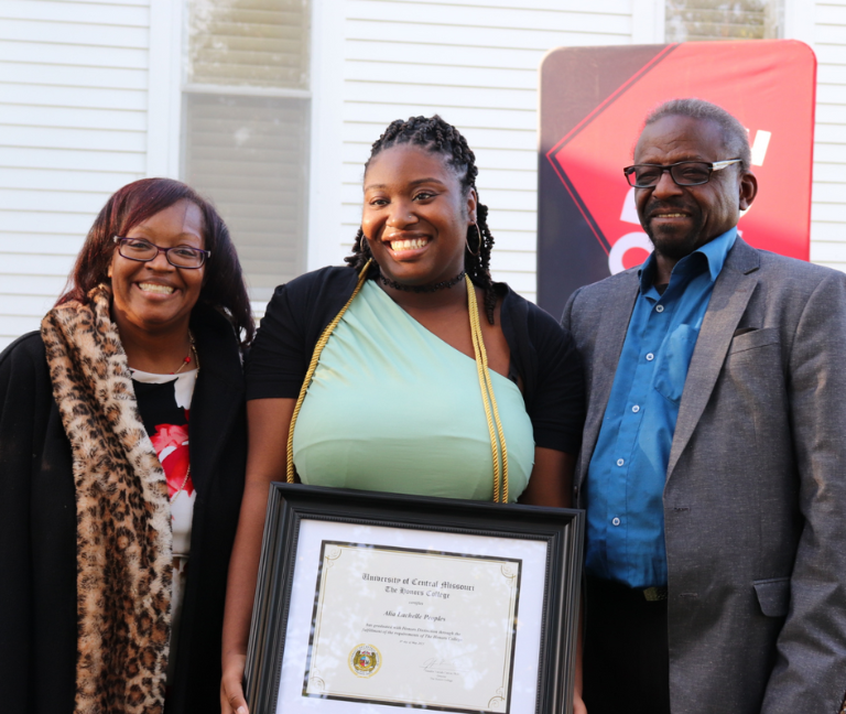 Honors Certificate Recipient Image of an Honors College student receiving an honors certificate standing inbetween her parents.