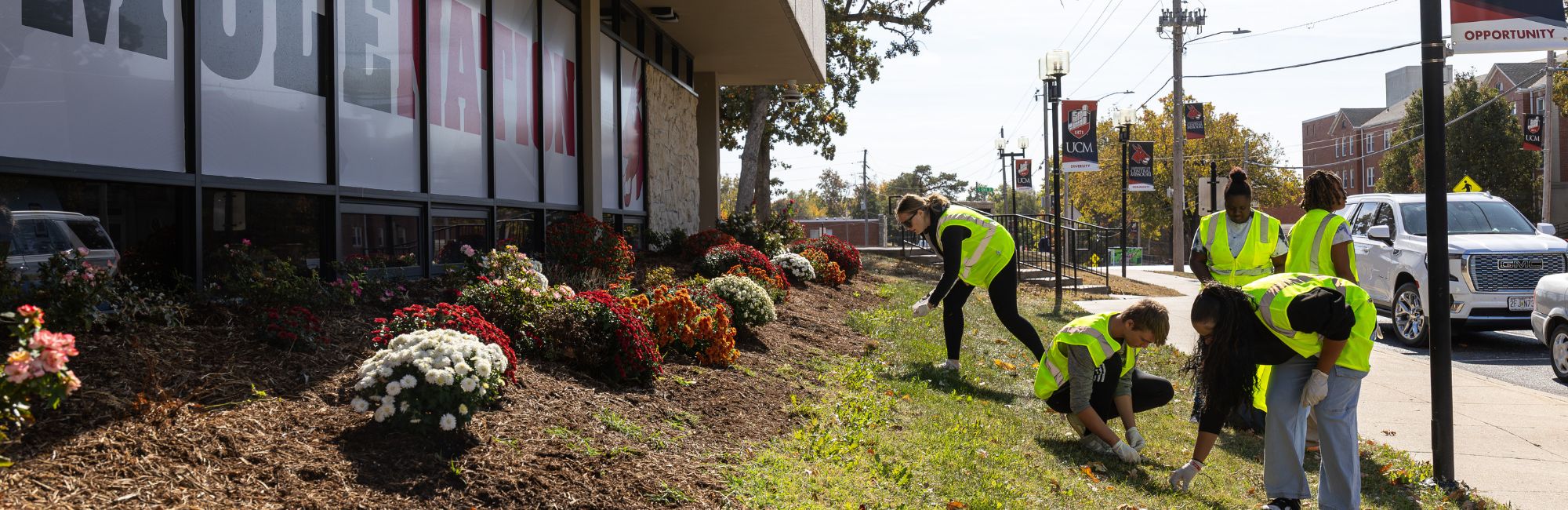 volunteers in safety vest picking up trash before Homecoming 2024