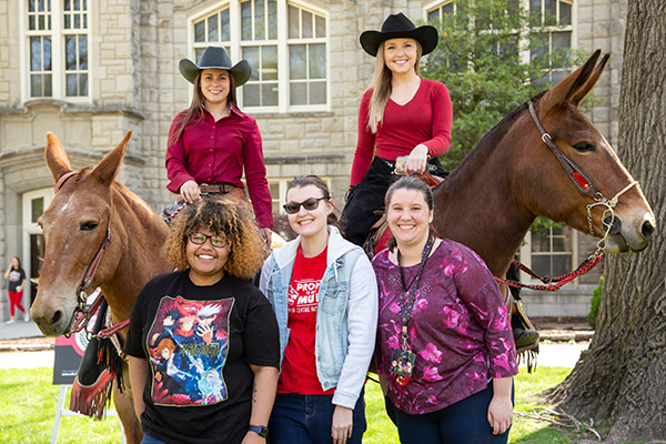 Three students posing with the UCM Mules and Muleriders.