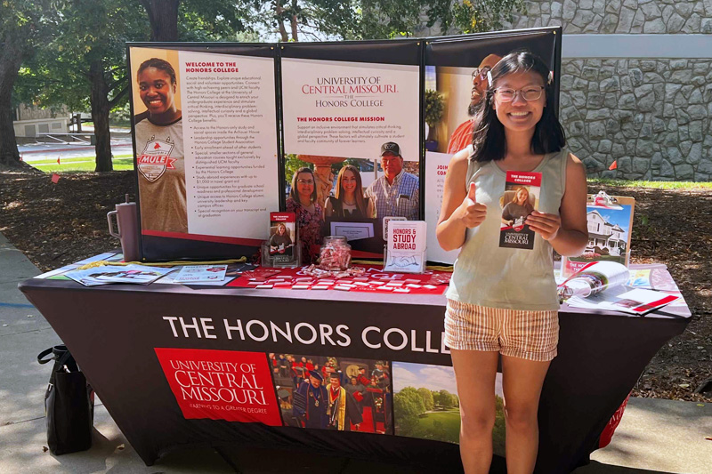 Honors College Promotional Table Honors student in front of promotional table.